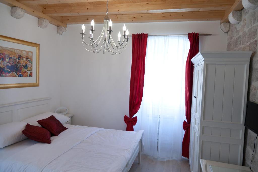 a bedroom with a bed with red curtains and a chandelier at Apartments Zoro in Dubrovnik