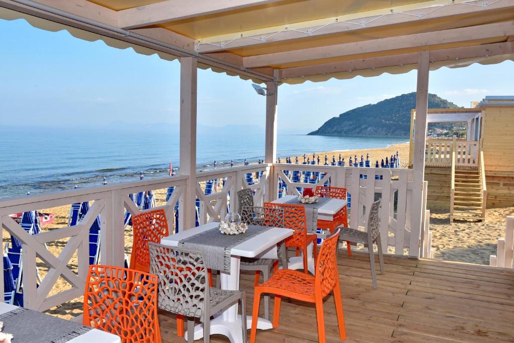 a patio with tables and chairs on the beach at Hotel Costa d'Oro in Santa Maria di Castellabate