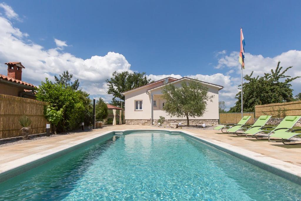 a swimming pool with chairs and a house at Villa Luka Nedešćina in Nedeščina