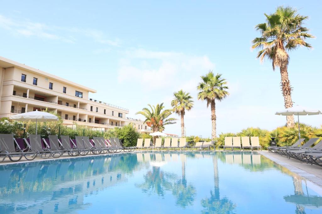 - une piscine dans un complexe avec des chaises et des palmiers dans l'établissement Golden Tulip Villa Massalia, à Marseille
