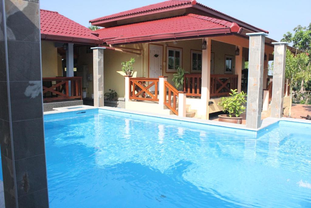 une grande piscine bleue devant une maison dans l'établissement Rimlay Park Resort, à Phatthalung
