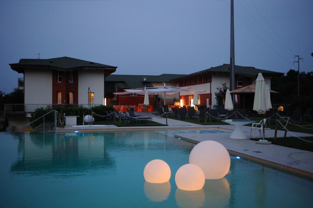 una piscina con luces en el agua por la noche en La Foresteria Canavese Golf & Country Club, en Torre Canavese