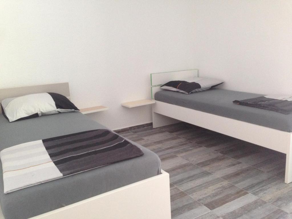2 łóżka w pokoju z białymi ścianami i drewnianą podłogą w obiekcie Rooms Chill Out Beach w Trogirze