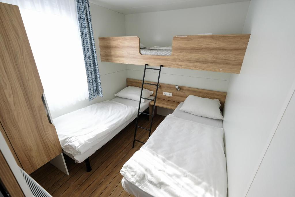 a small room with two bunk beds and a window at Terme Village - Mobile Homes in Čatež ob Savi