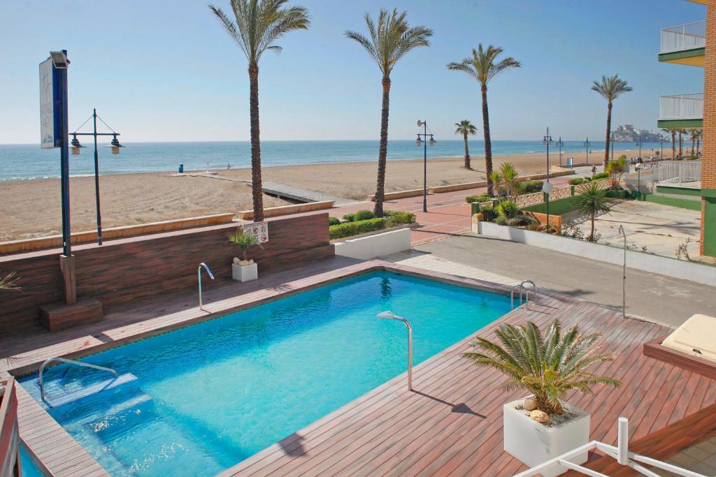 una piscina junto a una playa con palmeras en Sunday's Beach, en Peñíscola