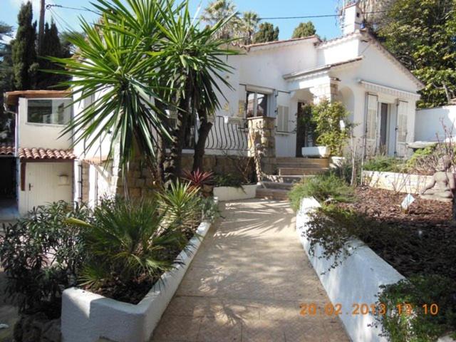 a white house with palm trees in front of it at Un coin de campagne en ville in Le Cannet