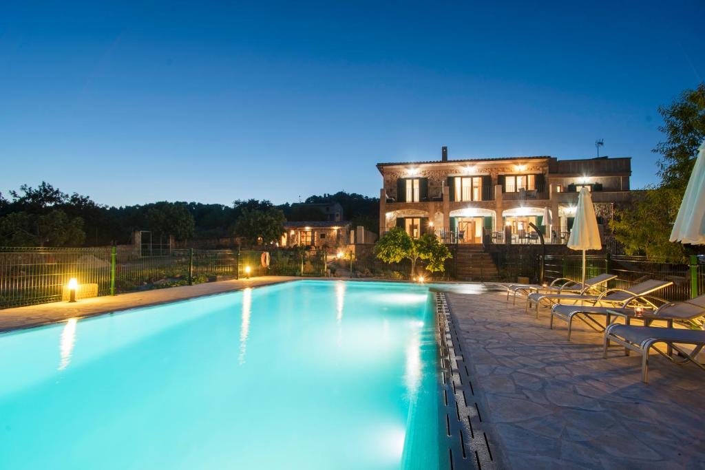 a swimming pool with chairs and a house in the background at Agroturismo Sa Marina in Alquería Blanca