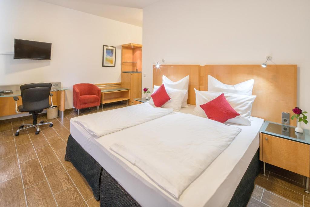 a bedroom with a large bed with red and white pillows at Taba Hotel in Kellinghusen