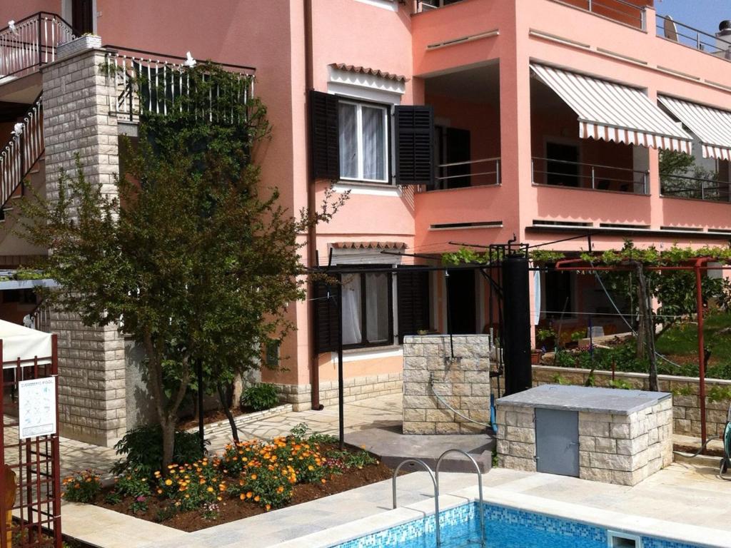 a house with a swimming pool in front of a building at Apartment Pula 8 in Veli Vrh