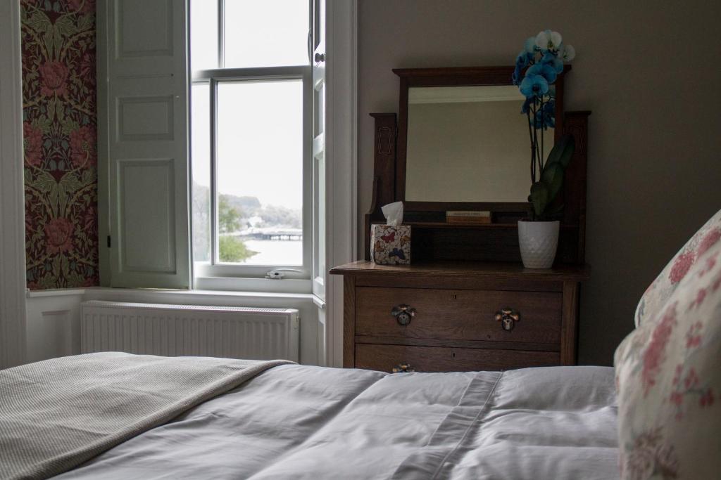 a bedroom with a bed and a mirror and a dresser at Pennygate Lodge in Craignure