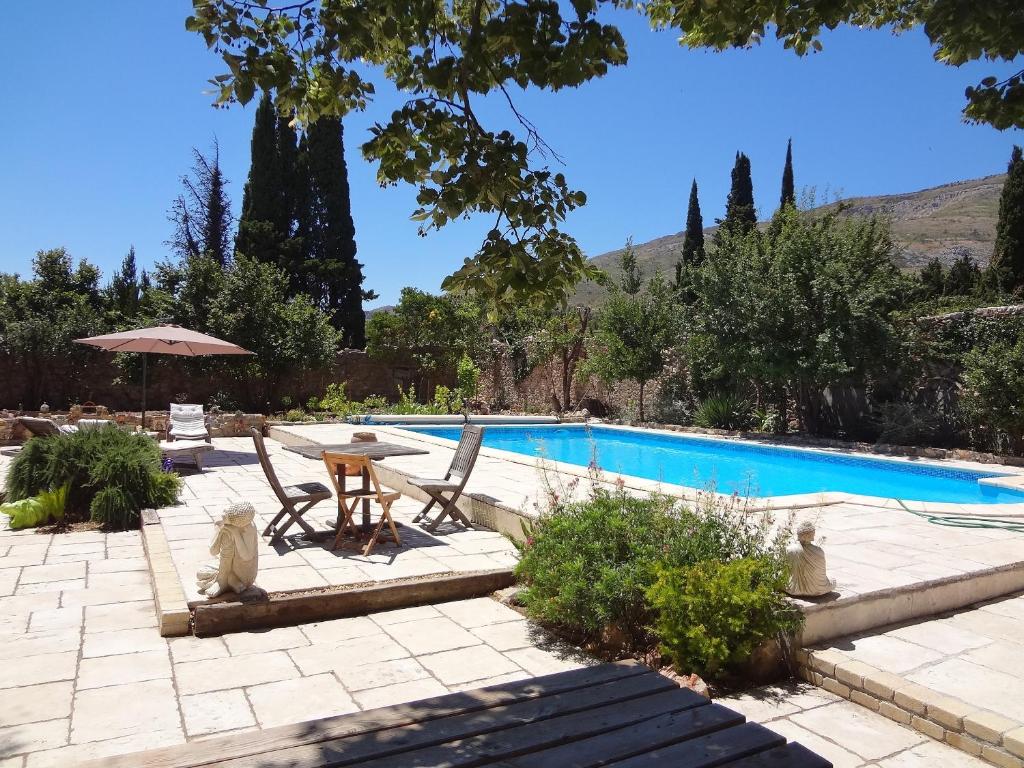 una piscina con tavolo, sedie e ombrellone di L Ancien Moulin à Huile a Tuchan