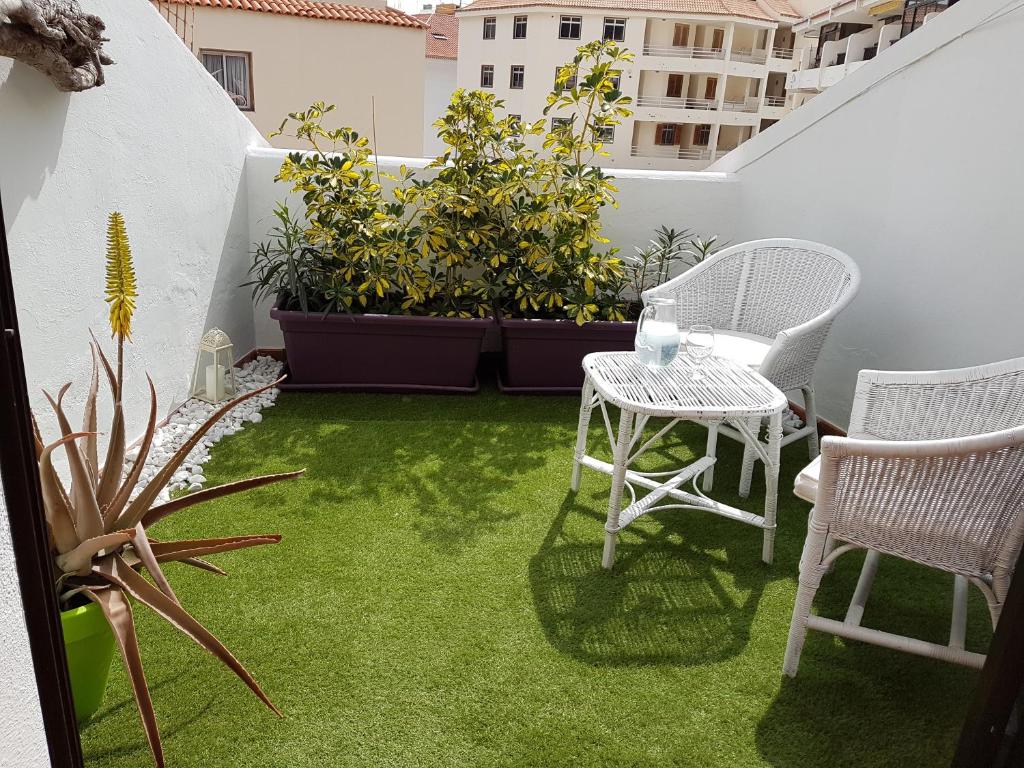 ロス・クリスティアーノスにあるLos Cristianos, Nirvana Apartamentoの小さなパティオ(芝生の上にテーブルと椅子付)
