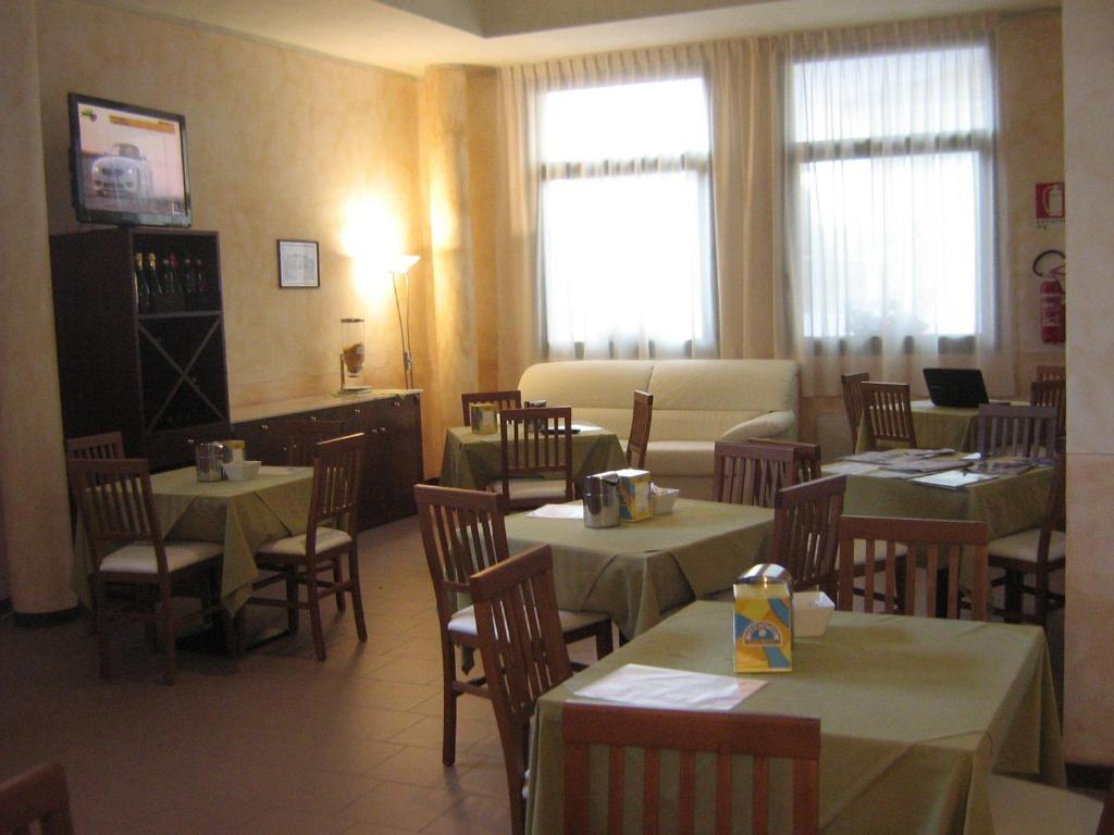 a dining room with tables and chairs and windows at Hostiliae Ciminiera Hotel in Ostiglia