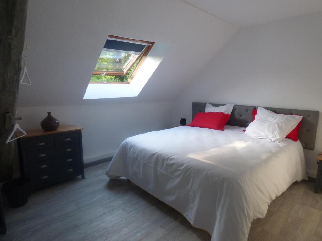 Schlafzimmer mit einem Bett mit roten Kissen und einem Fenster in der Unterkunft La bicoque en Puisaye in Saint-Amand-en-Puisaye