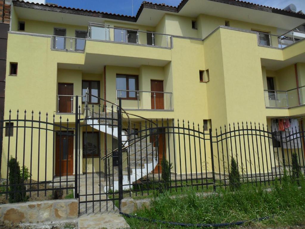 ein gelbes Gebäude mit einem Zaun davor in der Unterkunft Altay Guest House in Lozenets