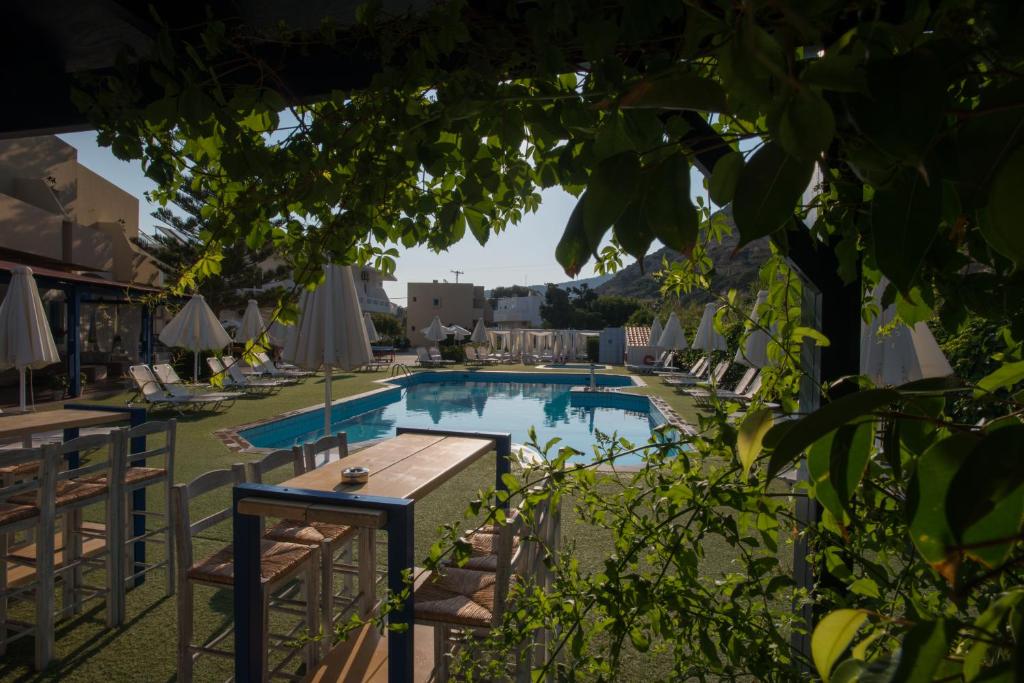 einen Pool in einem Hotel mit Stühlen und einem Tisch in der Unterkunft Fragiskos Hotel in Matala