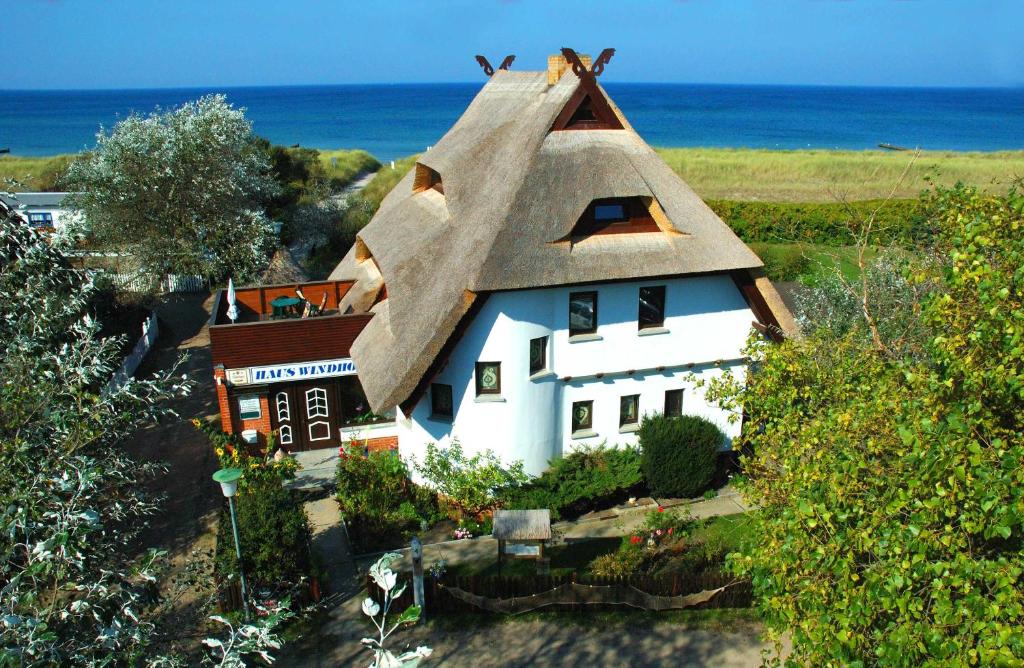 ein kleines weißes Haus mit einem Strohdach in der Unterkunft Haus Windhook in Dierhagen