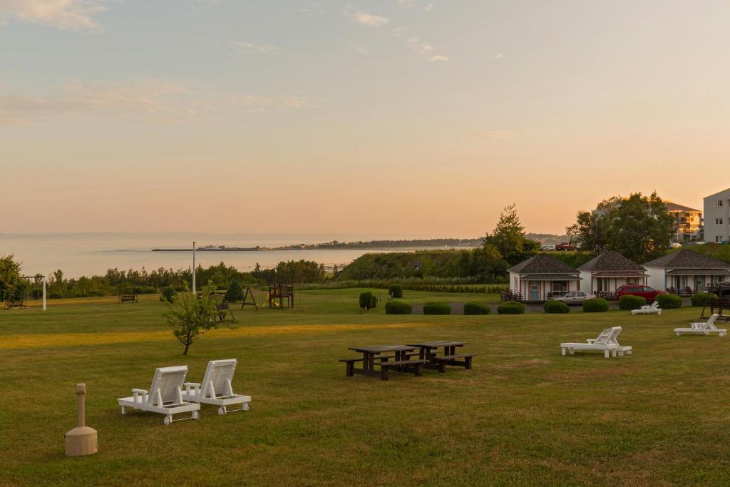 un groupe de chaises et de tables de pique-nique dans un champ dans l'établissement Motel au Fleuve d'Argent, à Rivière-du-Loup