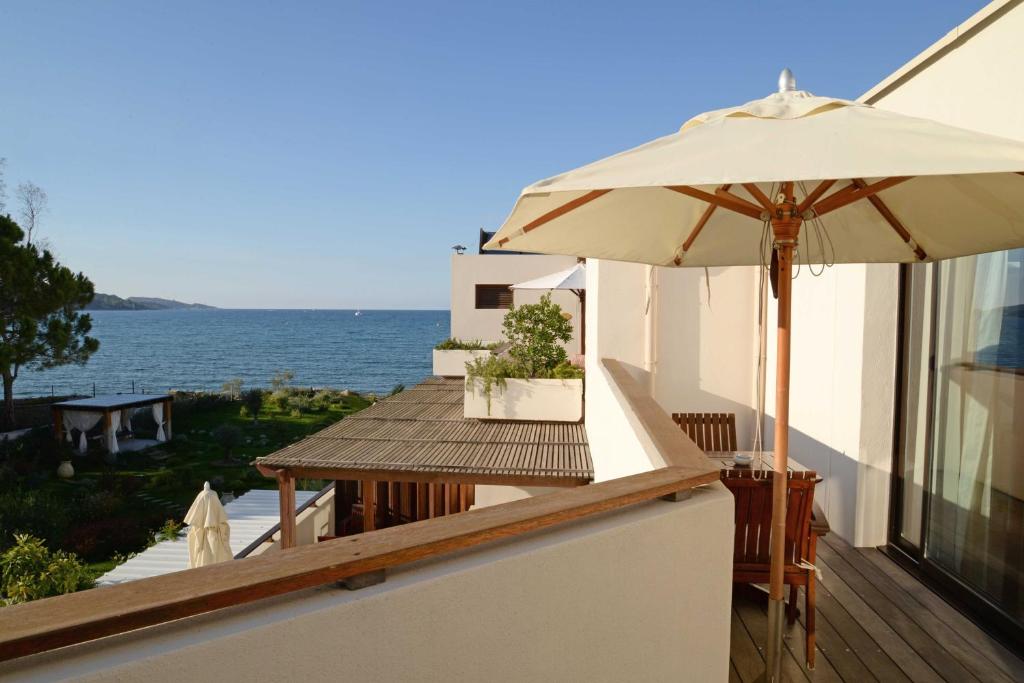 a patio with an umbrella and a table on a balcony at Hôtel La Roya in Saint-Florent