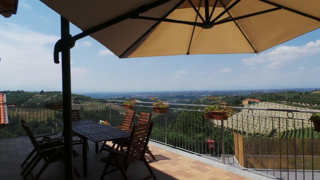 een patio met een tafel en stoelen en een parasol bij Agriostello delle Langhe in Farigliano