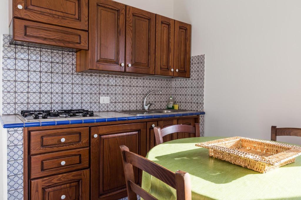 a kitchen with wooden cabinets and a table with a green table at Le Casette a Favignana in Favignana
