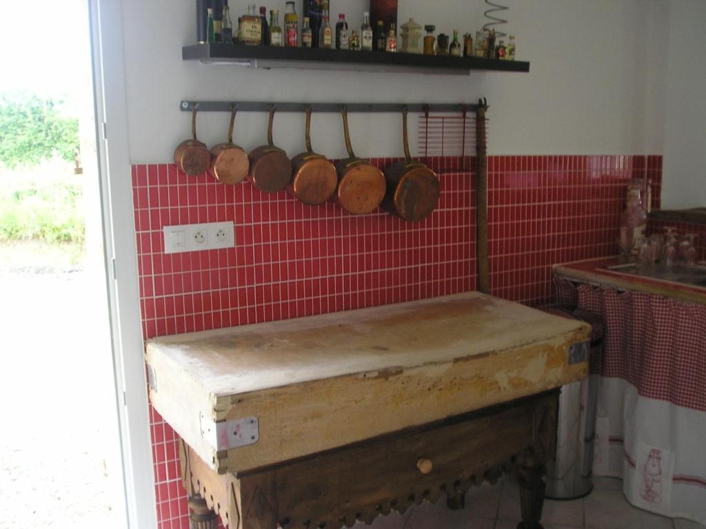a kitchen with a counter with pots and pans on the wall at Les Ecuries in Saint-Maurice-en-Cotentin