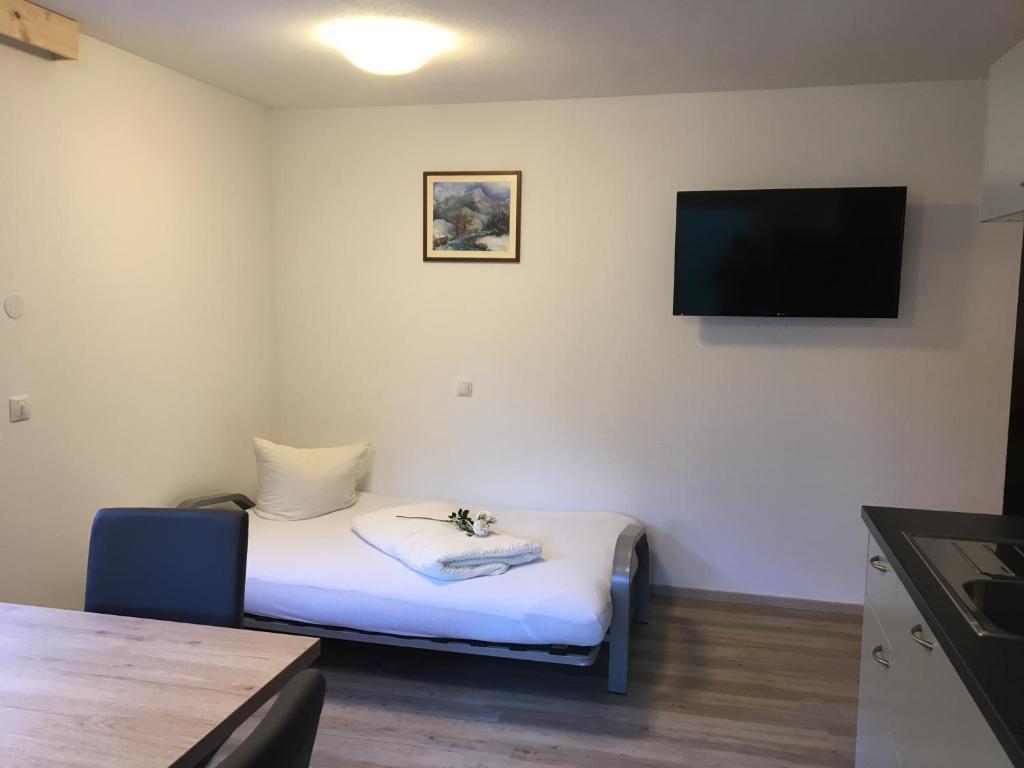 a small room with a bed and a flat screen tv at Haus Bergheim in Sankt Leonhard im Pitztal