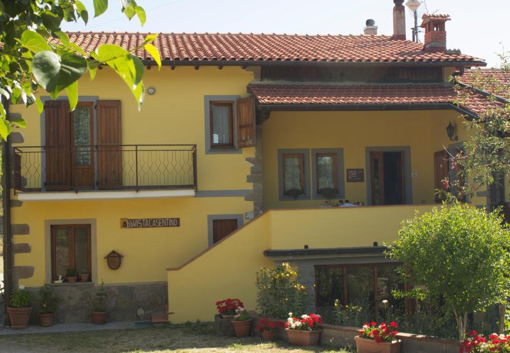 een geel huis met bloemen ervoor bij B&B Vista Casentino in Pratovecchio