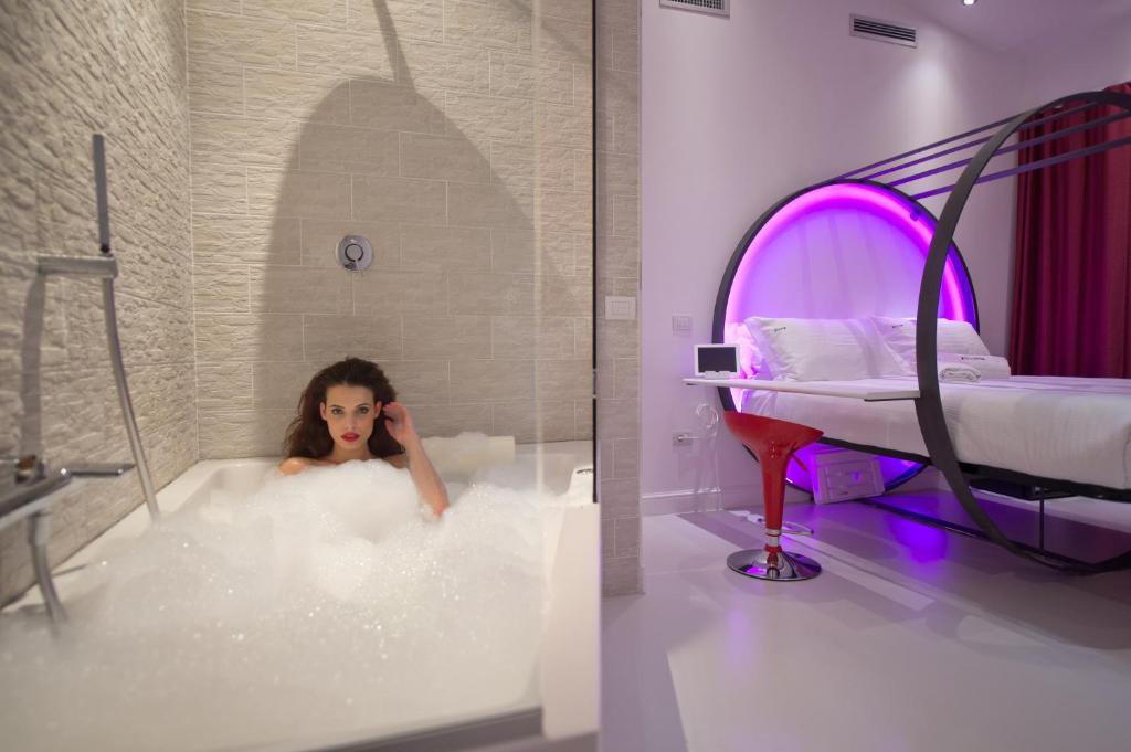 a woman sitting in a bath tub with a bed at iRooms Forum & Colosseum in Rome