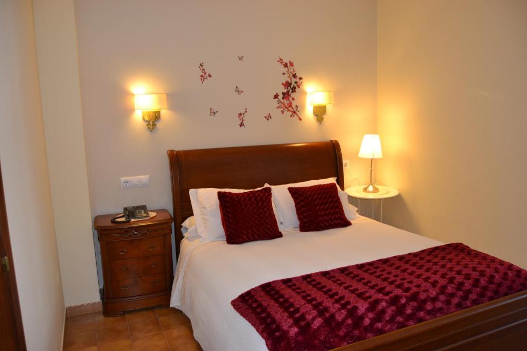 a bedroom with a large bed with red pillows at Hotel Nuevo Cachalote in Portonovo