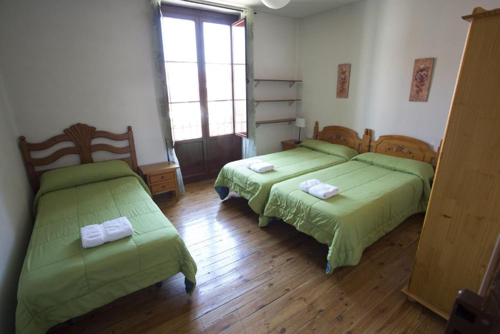 2 camas en una habitación con sábanas verdes en Pensión Sandoval, en León