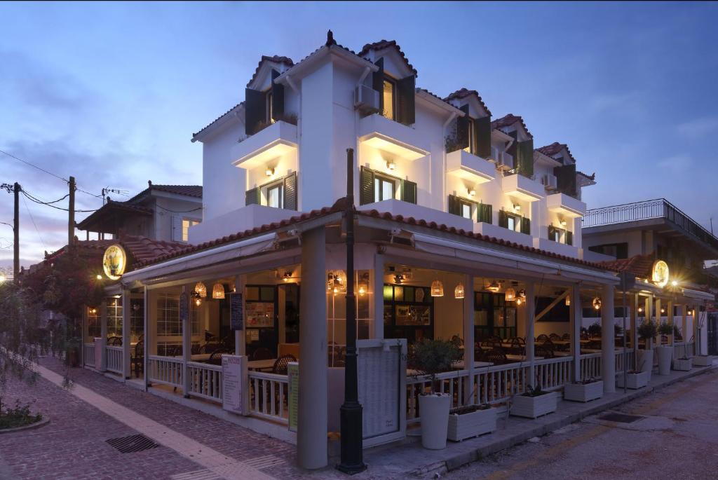 a large white building with a restaurant on a street at The Pines in Skala