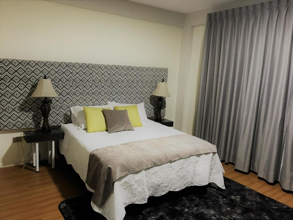 een slaapkamer met een groot bed met gele kussens bij Departamento De Lujo in Cochabamba