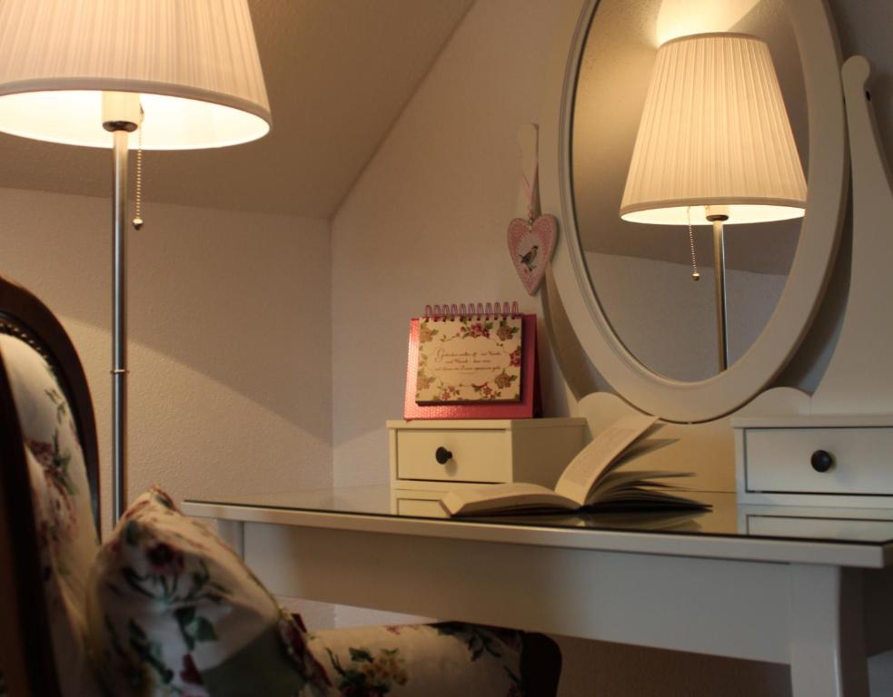 een tafel met een spiegel en een stoel met een boek bij Gästehaus Gebauer in Hornbach