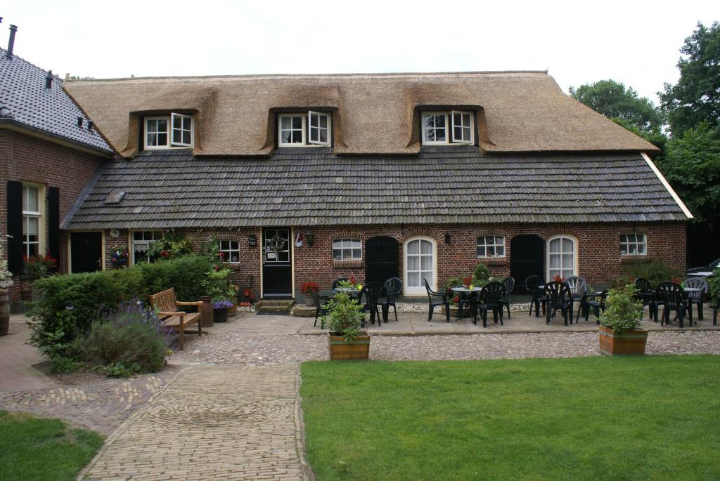 a large brick house with a patio with tables and chairs at Pension De Hoestinkhof in Markelo