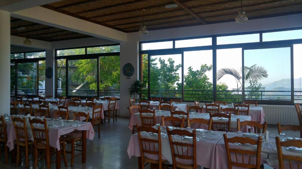 a dining room with tables and chairs and windows at Two Flowers Hotel in Pedoulas