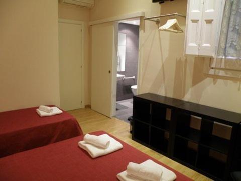 a room with two beds and a bathroom with a mirror at Center Gran Via in Barcelona