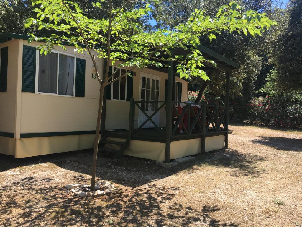 une petite maison avec un arbre en face dans l'établissement Mobile Homes Camping Biograd, à Biograd na Moru