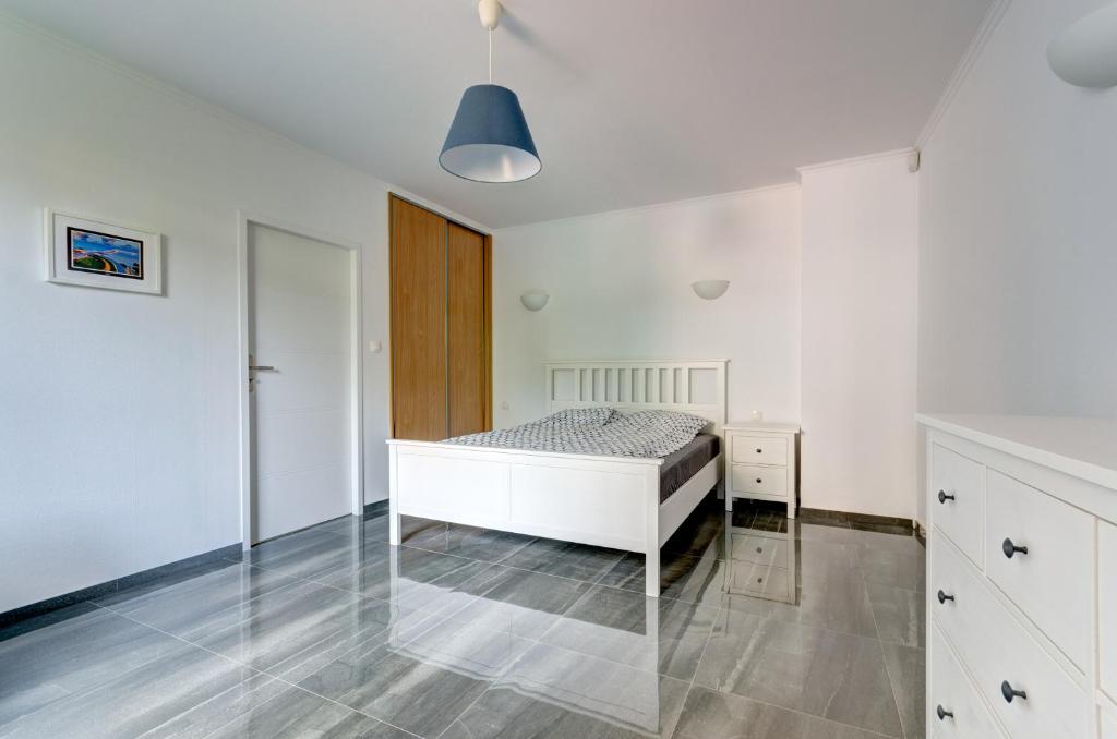 a white bedroom with a bed and a cabinet at Apartament Sopocki in Sopot