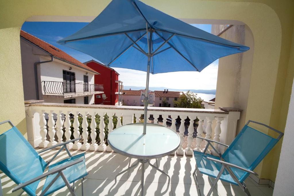 a table and two chairs and a blue umbrella on a balcony at Apartment Crikvenica, Vinodol 2 in Crikvenica