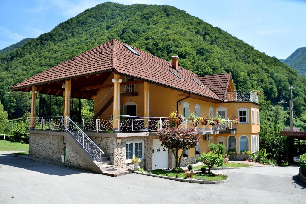 a house with a balcony and a mountain in the background at Apartment Sotočje in Dolenja Trebuša