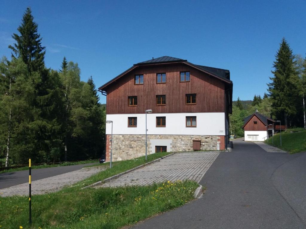 un granero grande marrón y blanco en una carretera en Apartmán Špičák Sruby en Špičák