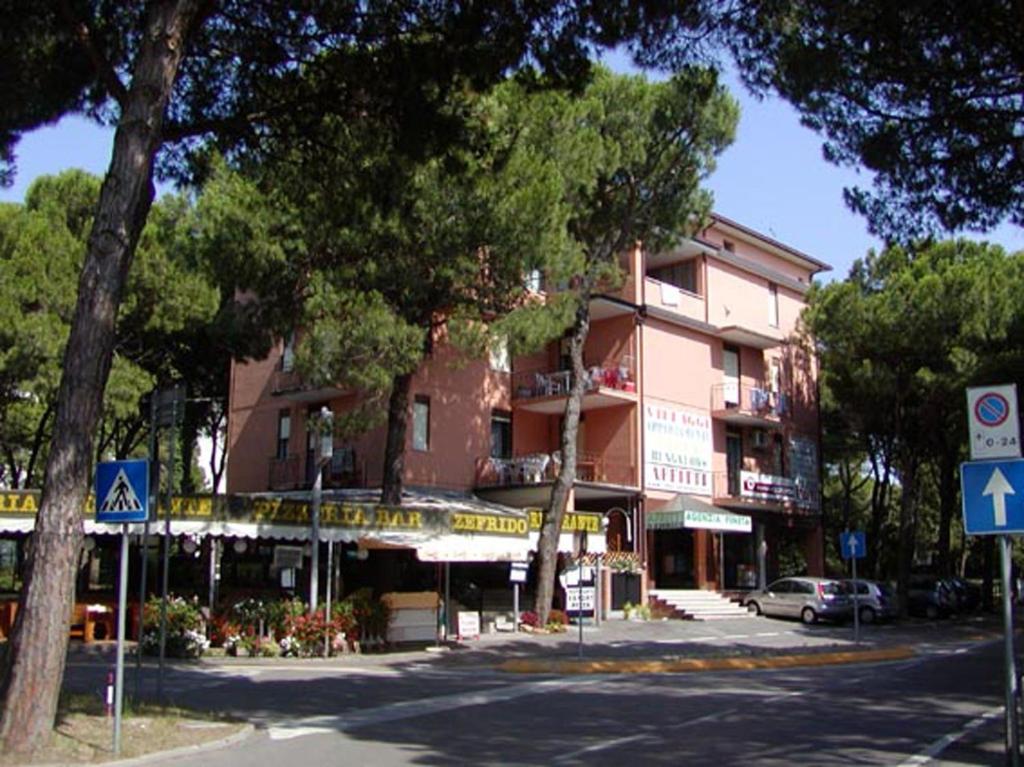 un edificio sul lato di una strada con un albero di Apartments in Rosolina Mare 24870 a Rosolina Mare