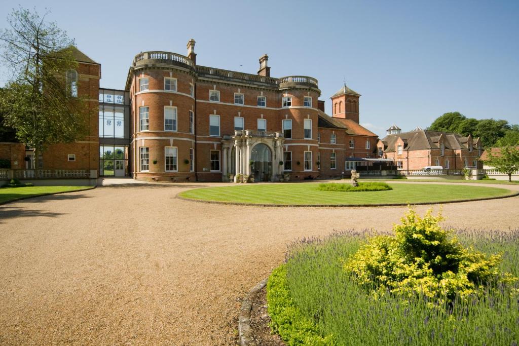 a large red brick building with a large driveway at Oakley Hall Hotel in Basingstoke