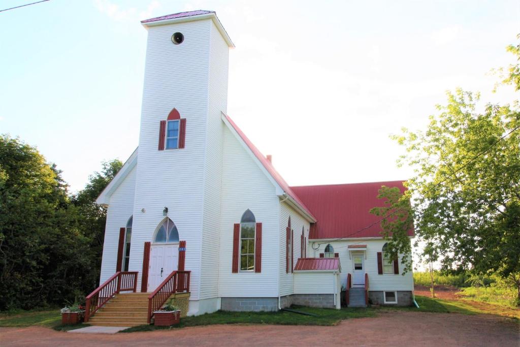 een witte kerk met een rood dak bij The Church House in New Brunswick in Cape Tormentine