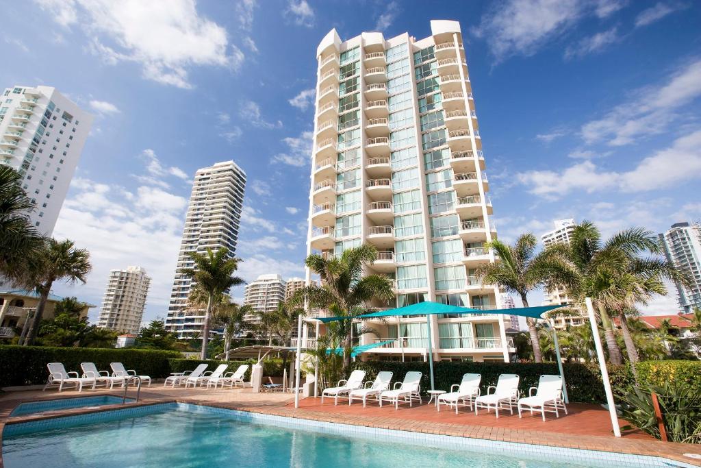 een zwembad met stoelen en een hoog gebouw bij Maldives Resort Main Beach, Gold Coast in Gold Coast