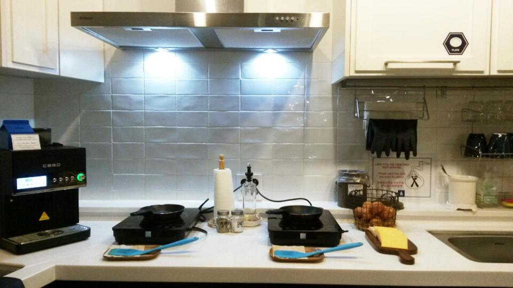 um balcão de cozinha com panelas e frigideiras e um lavatório em Blueboat Hostel Gyeongju em Gyeongju