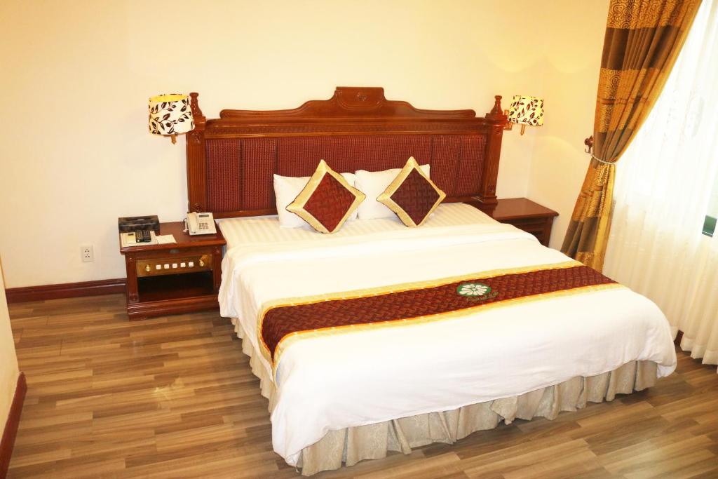 Schlafzimmer mit einem großen Bett mit einem Kopfteil aus Holz in der Unterkunft Central Hotel in Quảng Ngãi