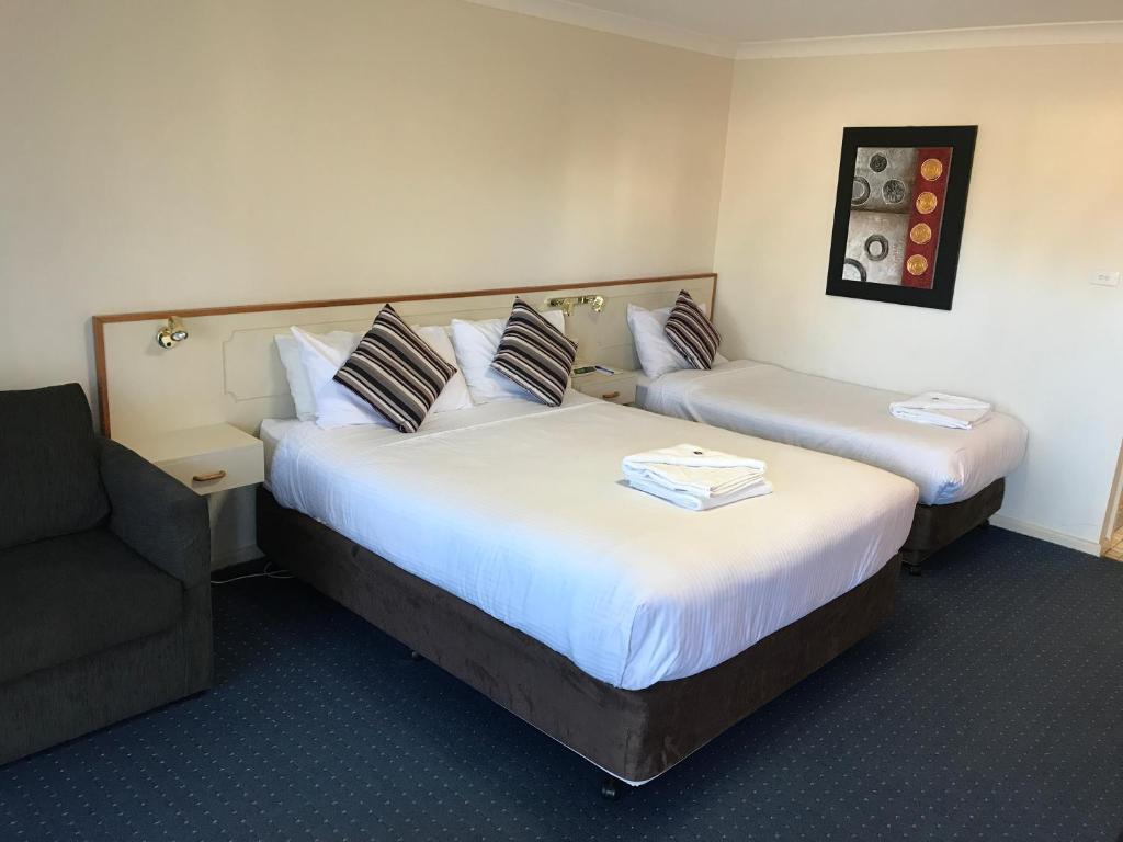 a hotel room with two beds and a chair at Orange Motor Lodge in Orange