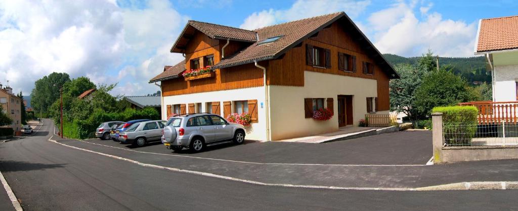 une maison avec des voitures garées dans un parking dans l'établissement Lacroisette, à Gérardmer